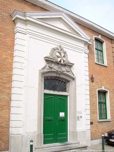 Spermalie BRUGGE foto De segmentbogige hoofdingang met een omlijsting in blauwe steen dateert uit 1770. Ze is voorzien van een met rocailles versierde cartouche en een frontonbekroning.